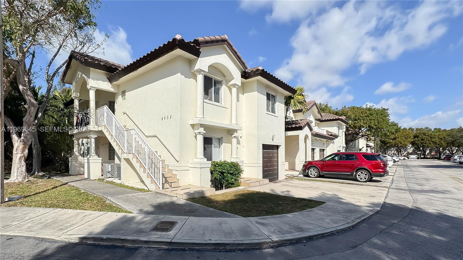 A two-story stucco building with a tiled roof, exterior staircase, and an attached garage — 8902 NW 109th Ct # 1203, Doral FL 33178, DORAL, FL