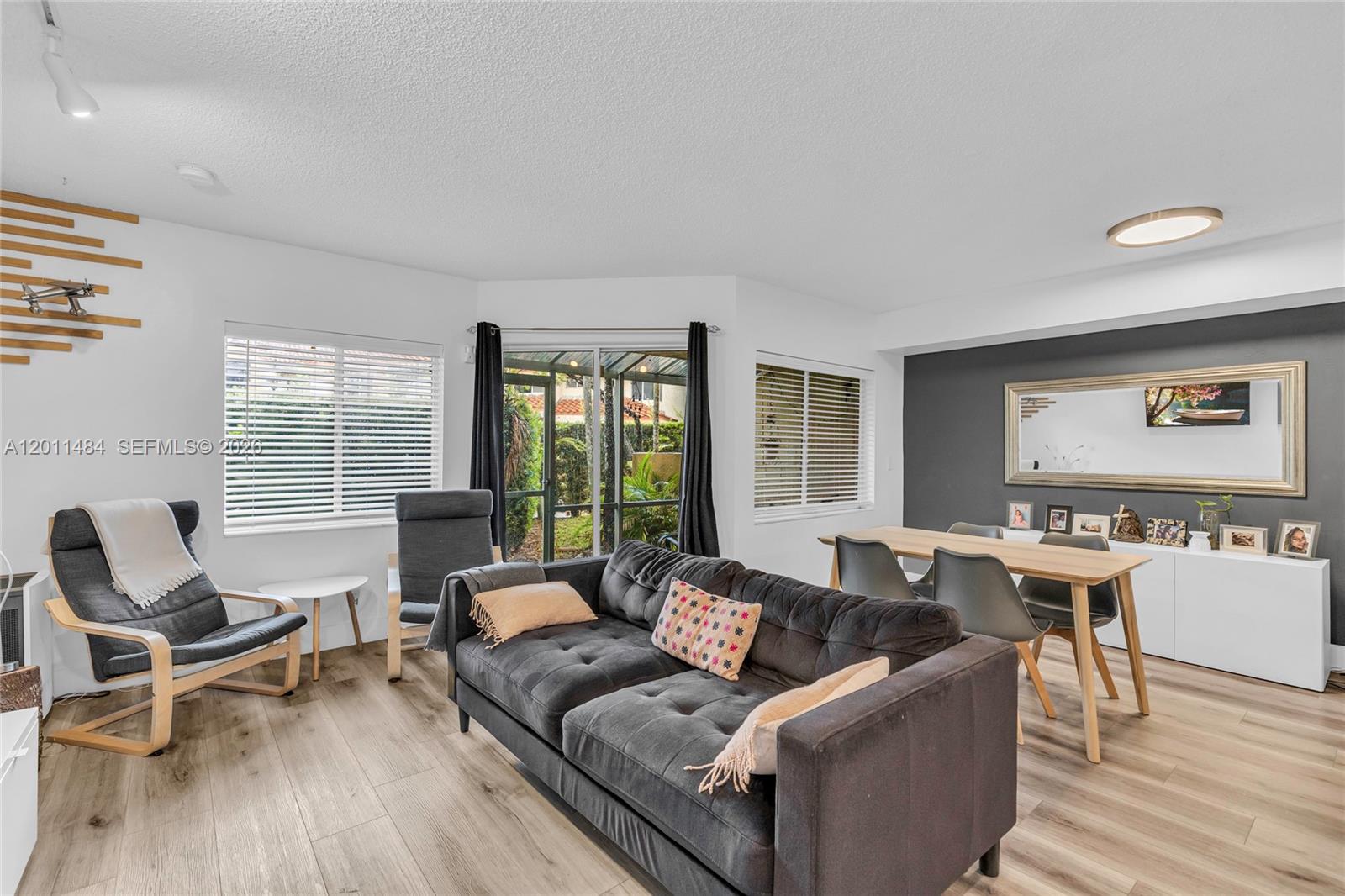 A living room with a grey sofa, wood-look flooring, and a staircase with white railings — 7874 NW 7th Ct, Plantation FL 33324, PLANTATION, FL