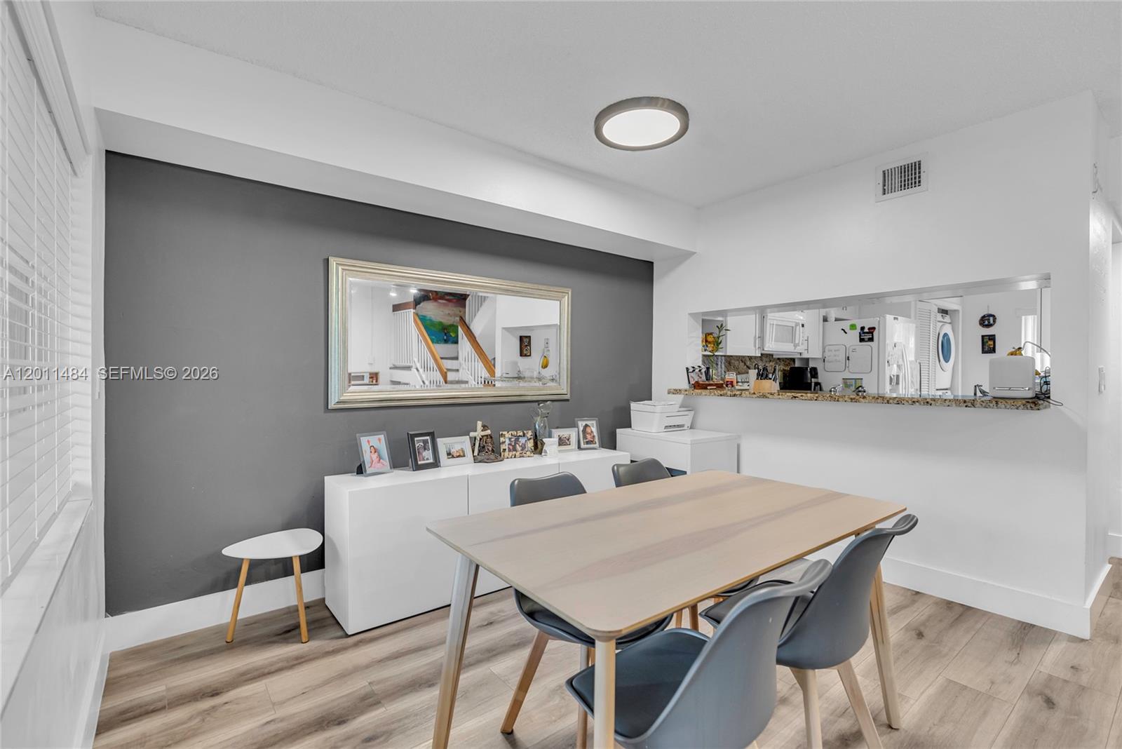 A living and dining room with wood-look flooring, a gray sofa, and a sliding door — 7874 NW 7th Ct, Plantation FL 33324, PLANTATION, FL