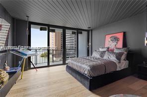 A modern bedroom features dark gray walls, a slatted ceiling, and a balcony with water views — 770 NE 69th St # 6E, Miami FL 33138, MIAMI, FL