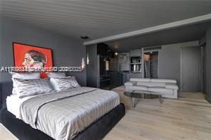 A modern bedroom with a large bed, grey walls, and an adjacent seating area — 770 NE 69th St # 6E, Miami FL 33138, MIAMI, FL