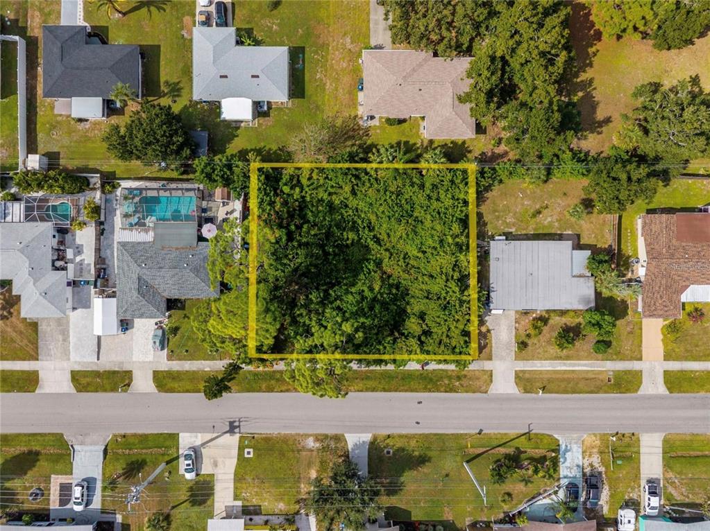 An aerial view shows a vacant, tree-covered residential lot outlined in yellow between two houses — 31 W SEMINOLE DRIVE, VENICE, FL