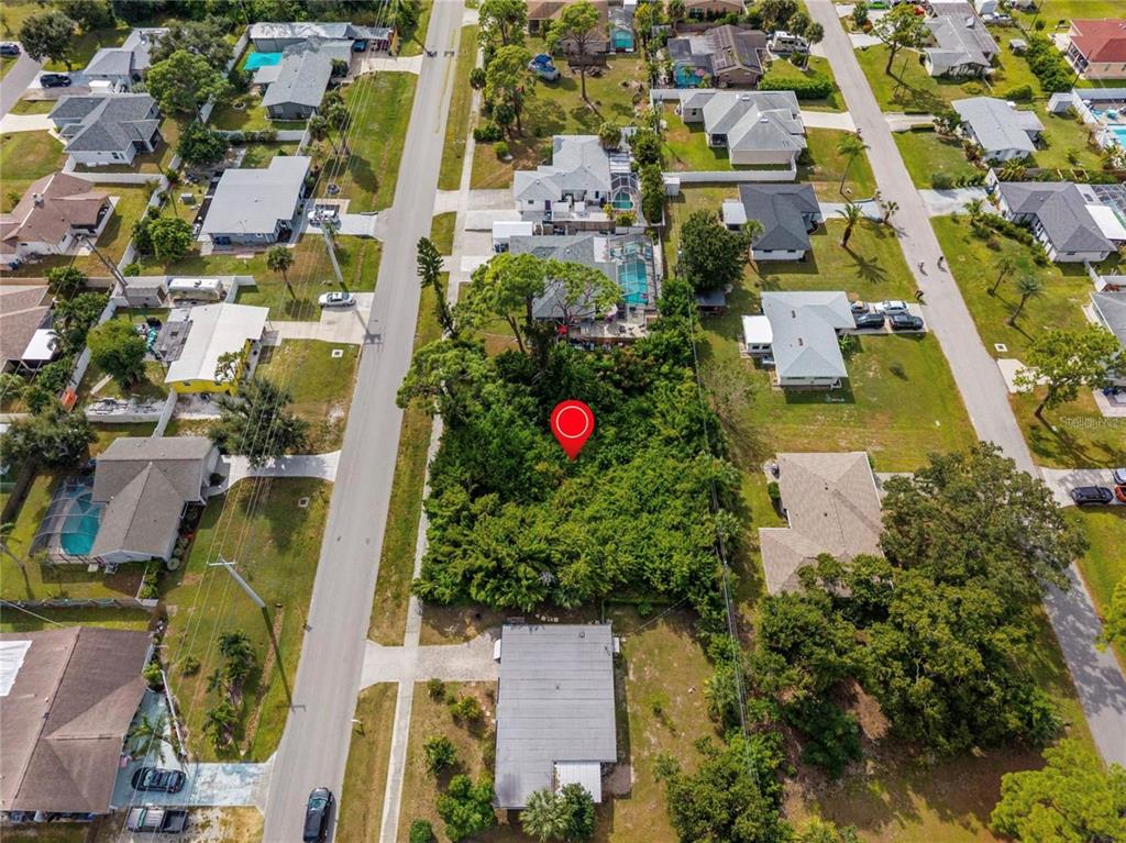 An aerial view shows a vacant, tree-covered lot marked by a red pin in a neighborhood — 31 W SEMINOLE DRIVE, VENICE, FL