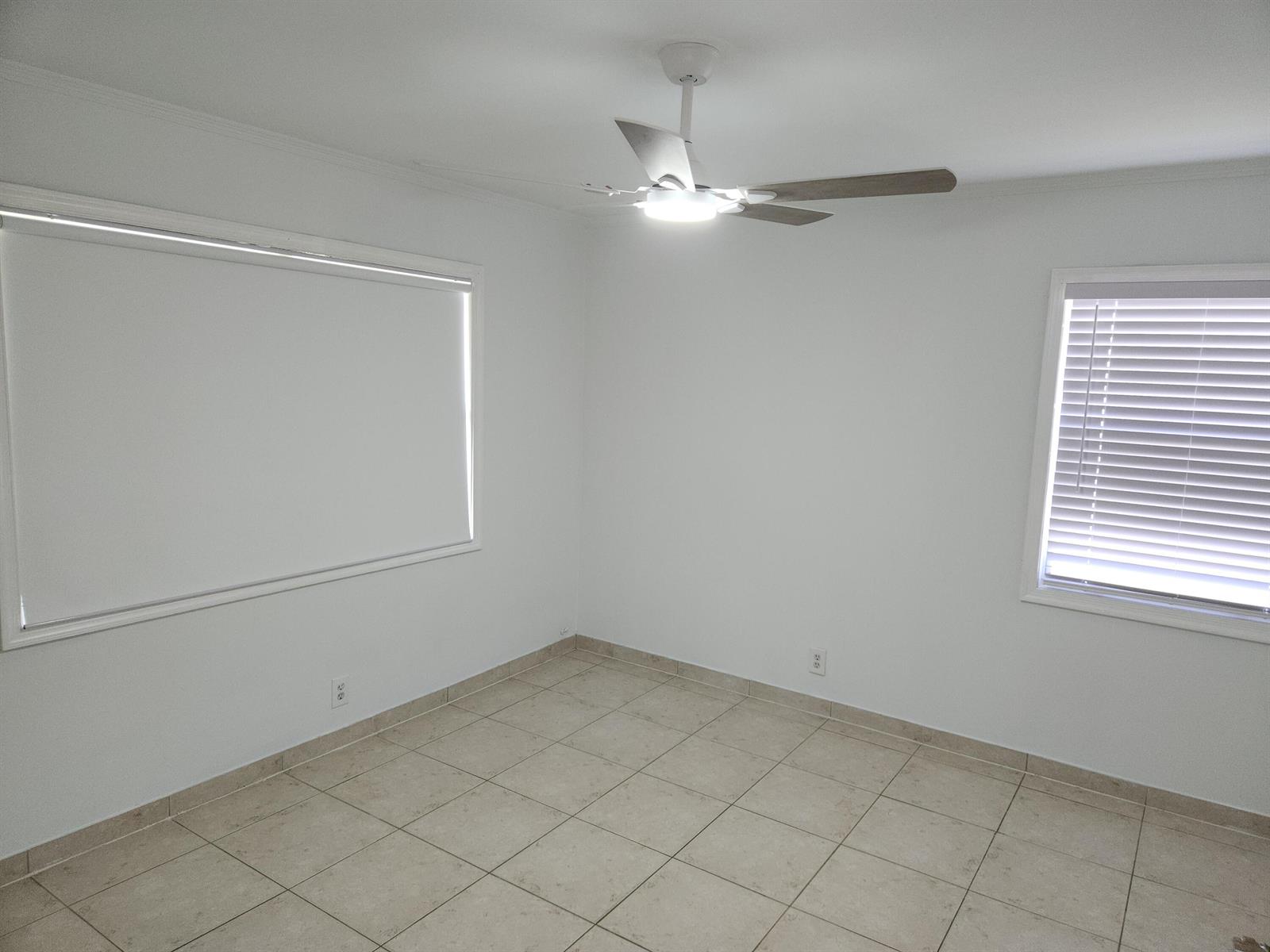 An empty room with white walls, tile flooring, a ceiling fan, and two windows — 210 NW 13th Avenue, Delray Beach FL 33444, DELRAY BEACH, FL