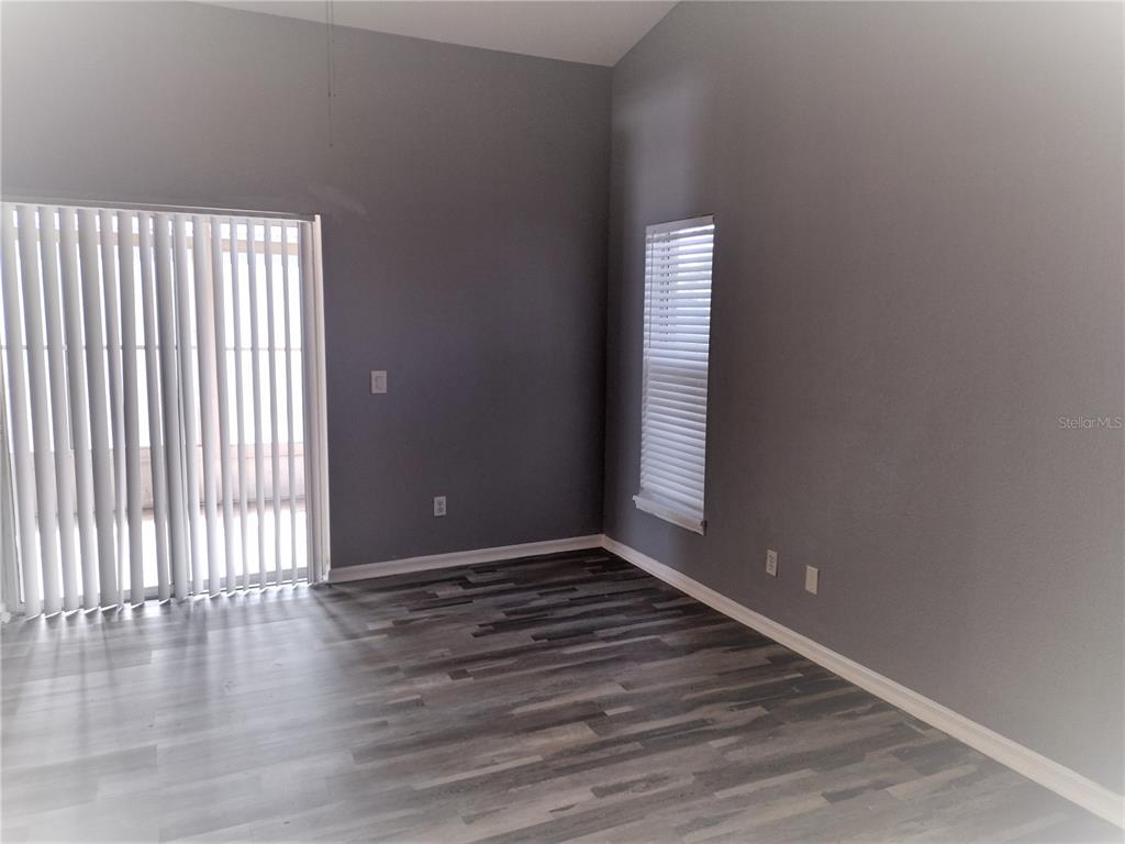 An empty room features gray walls, wood-look flooring, a sliding glass door, and a window — 2358 BLUE SAPPHIRE CIRCLE, ORLANDO, FL