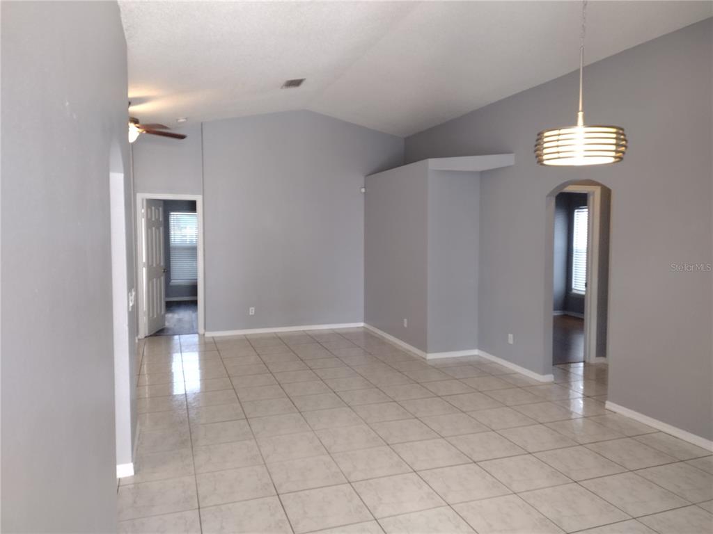 An empty room with gray walls, vaulted ceilings, tile flooring, and two arched doorways — 2358 BLUE SAPPHIRE CIRCLE, ORLANDO, FL