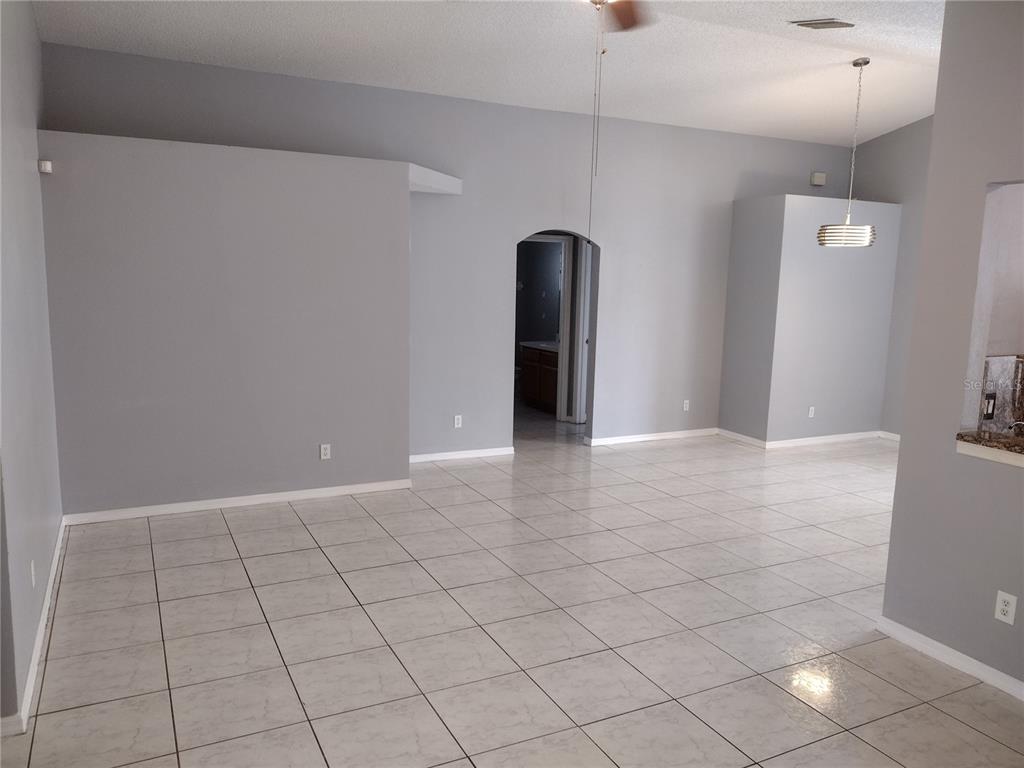An empty room with light gray walls, white trim, and light-colored square floor tiles — 2358 BLUE SAPPHIRE CIRCLE, ORLANDO, FL