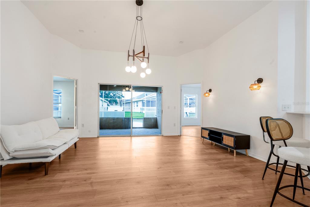 A living room with light wood floors, a white sofa, and a modern chandelier — 2705 WILLOW GLEN CIRCLE, KISSIMMEE, FL