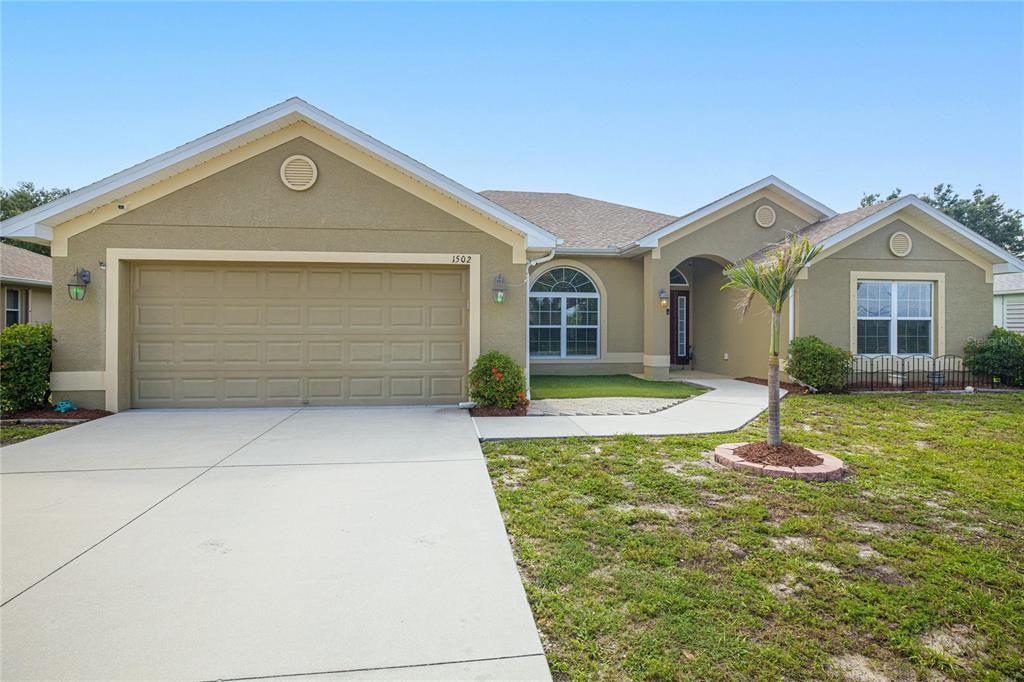 A single-story house with a tan stucco exterior, a two-car garage, and a palm tree — 1502 NAVIGATOR ROAD, PUNTA GORDA, FL