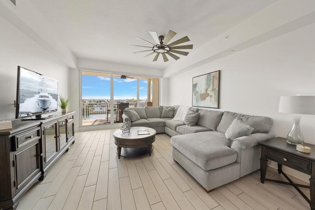 A living room features a gray sectional sofa, a coffee table, and a balcony view — 125 ISLAND WAY UNIT 402, CLEARWATER BEACH, FL
