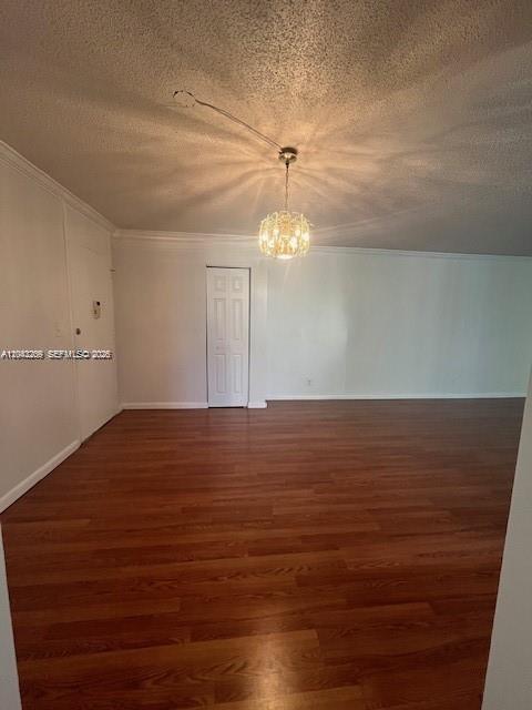 An empty room with wood-look flooring, a white door, and a hanging crystal light fixture — MIAMI, FL