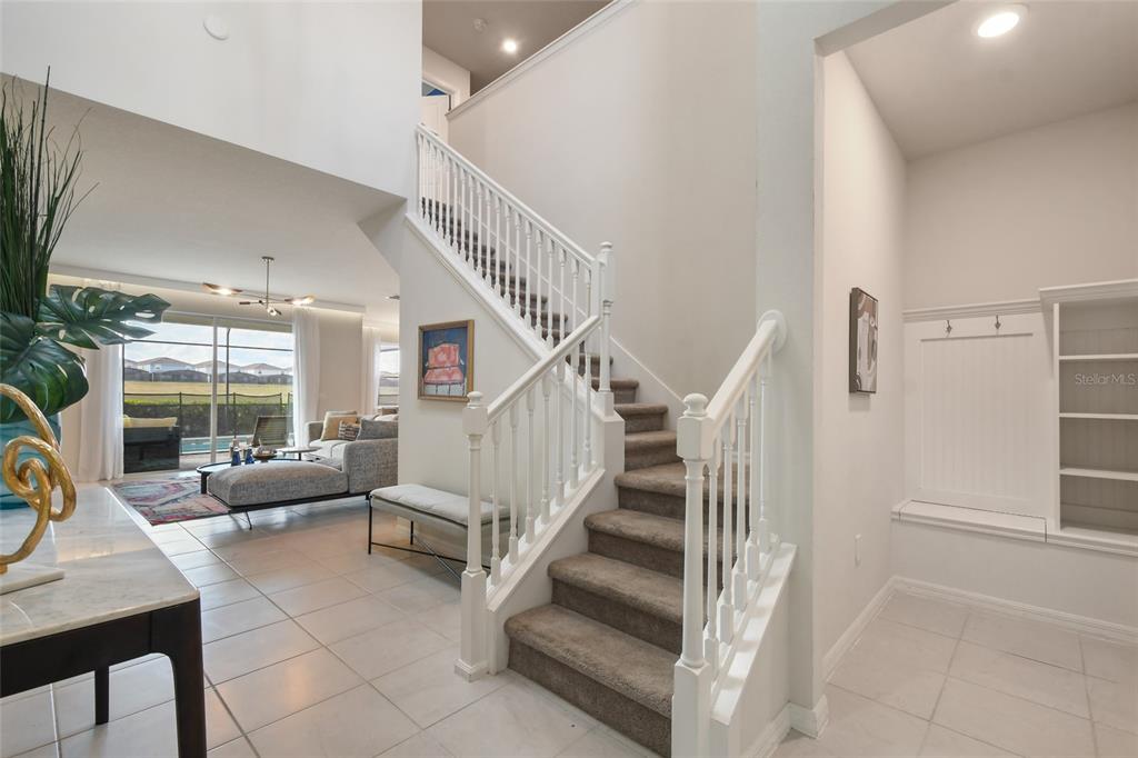 A staircase with carpeted steps leads to an upper level in a bright, tiled foyer — 1180 ALOHA BOULEVARD, DAVENPORT, FL