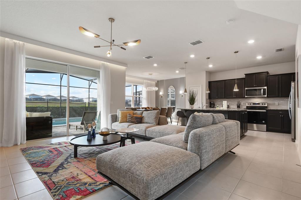 An open-concept living room and kitchen featuring a large sectional, area rug, and sliding doors — 1180 ALOHA BOULEVARD, DAVENPORT, FL