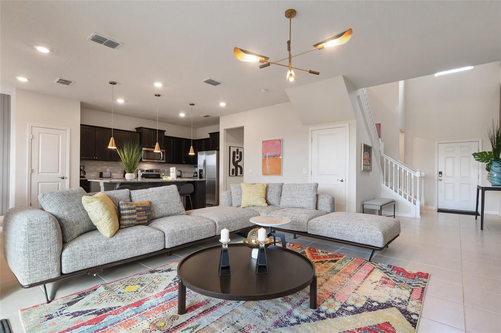 A living room with a grey sectional sofa, a round coffee table, and an open kitchen — 1180 ALOHA BOULEVARD, DAVENPORT, FL