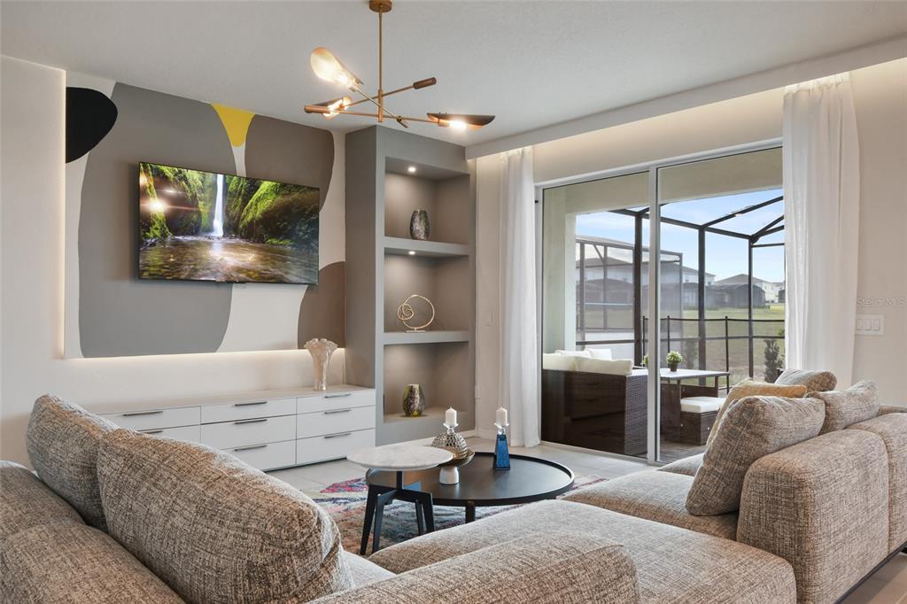 A living room features a gray accent wall with a television, built-in shelving, and patio access — 1180 ALOHA BOULEVARD, DAVENPORT, FL