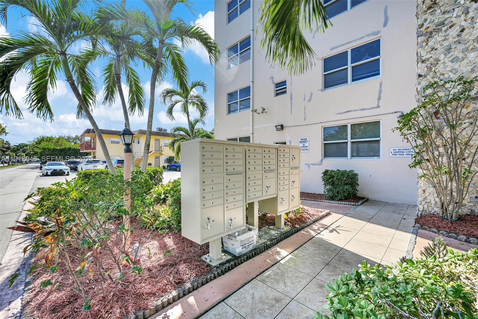 An outdoor view of a beige apartment building with a cluster of metal mailboxes — 1830 Dixieanna St # 506, Hollywood FL 33020, HOLLYWOOD, FL