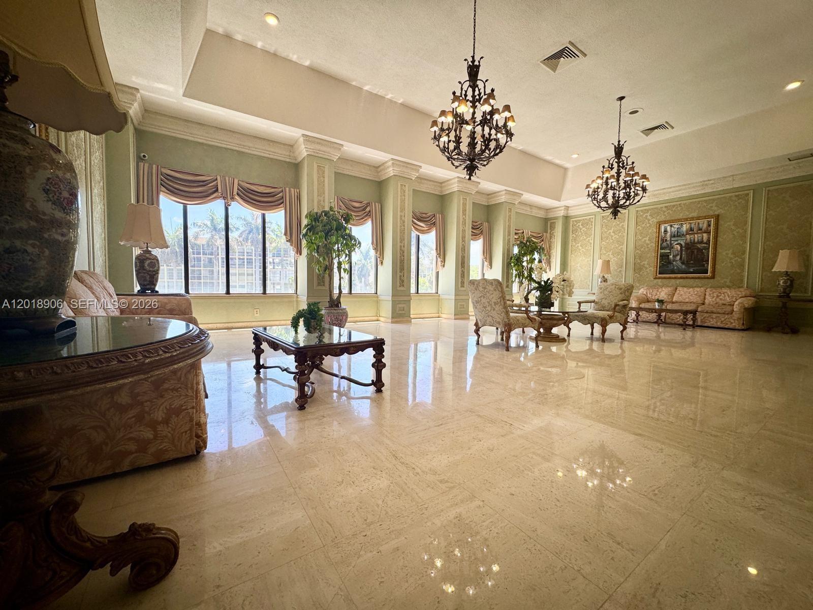 A dining area with a glass table and white chairs sits before an open kitchen — 600 Three Islands Blvd, Hallandale Beach FL 33009, HALLANDALE BEACH, FL