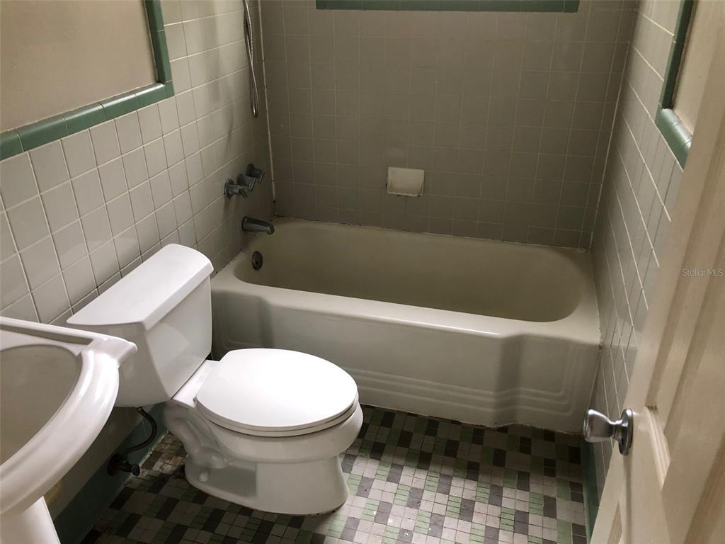 A bathroom features a white toilet, a pedestal sink, and a bathtub with tiled walls — 304 NW 36TH STREET, GAINESVILLE, FL
