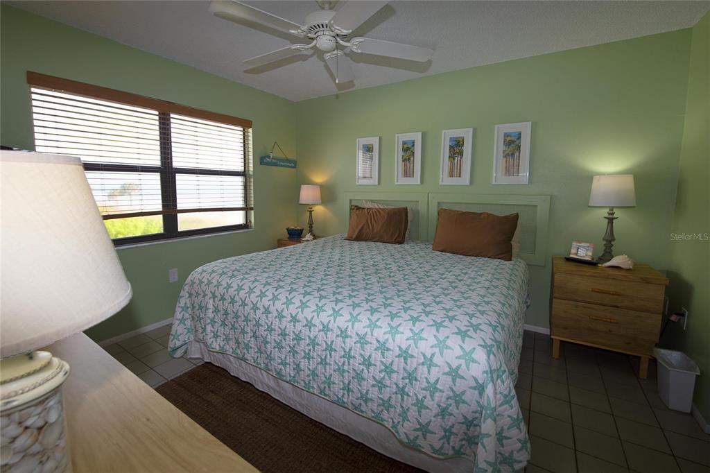 A bedroom features a king bed with a starfish quilt, green walls, and tile flooring — 1571 S ATLANTIC AVENUE UNIT 312, NEW SMYRNA BEACH, FL