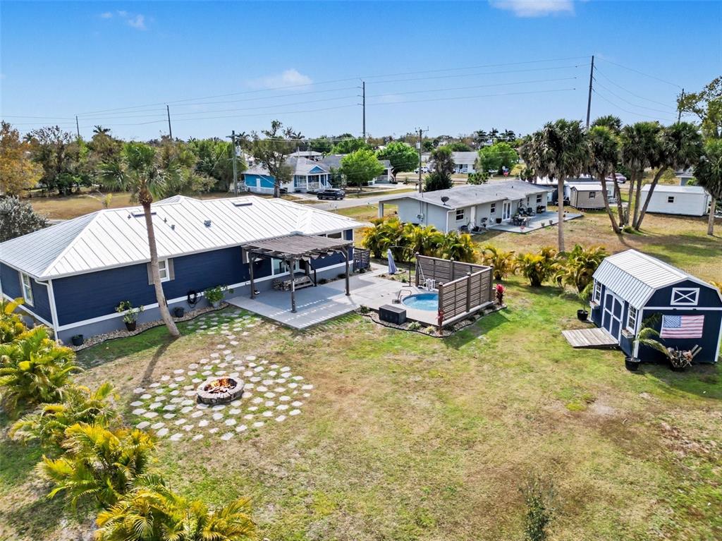 An aerial view of a blue house with a backyard patio, hot tub, and shed — 410 E HENRY STREET, PUNTA GORDA, FL