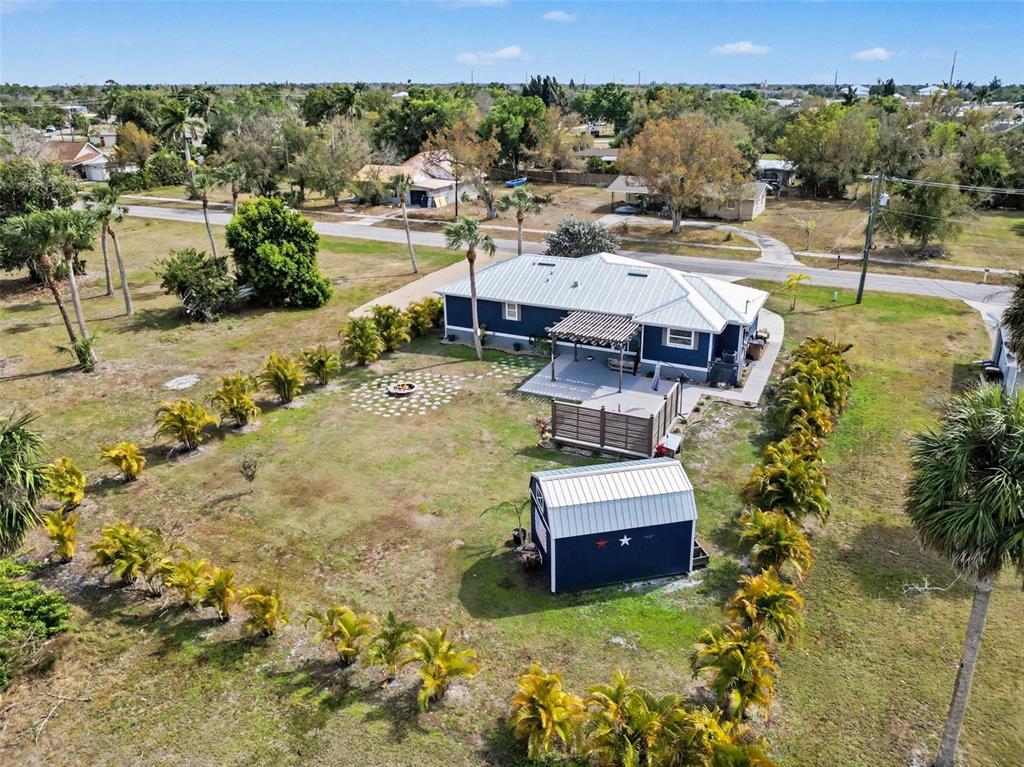 An aerial view shows a blue house with a metal roof, patio, and detached shed — 410 E HENRY STREET, PUNTA GORDA, FL