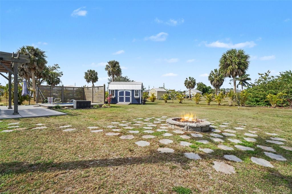A backyard features a fire pit, a blue storage shed, and a wooden pergola — 410 E HENRY STREET, PUNTA GORDA, FL