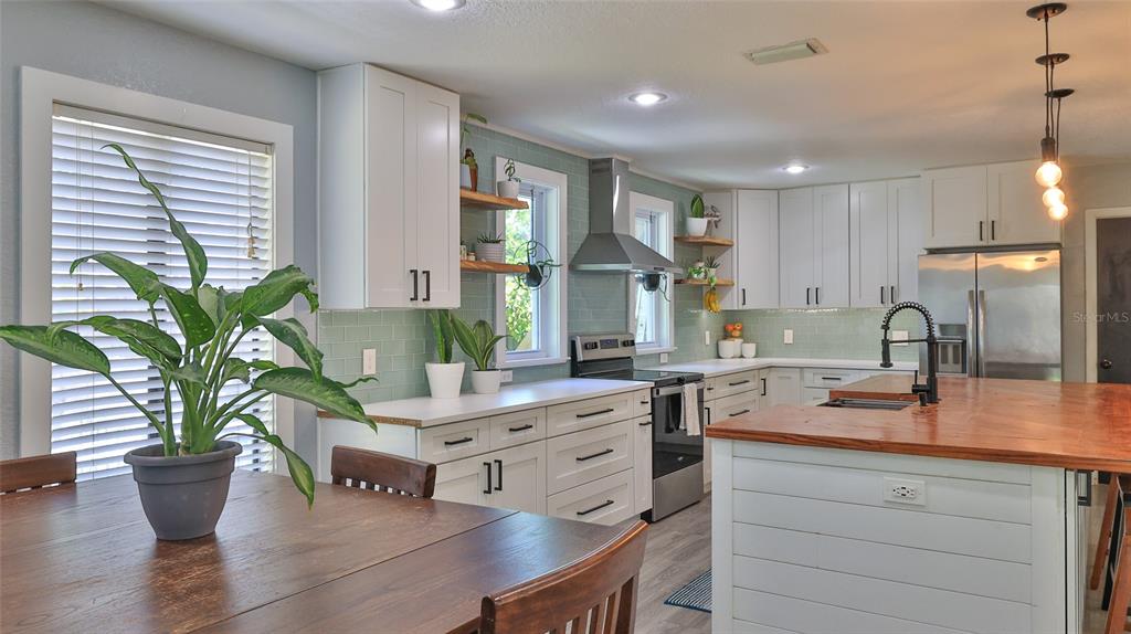 A kitchen features white cabinets, a light green subway tile backsplash, and a wood island — 2766 DATE PALM DRIVE, EDGEWATER, FL