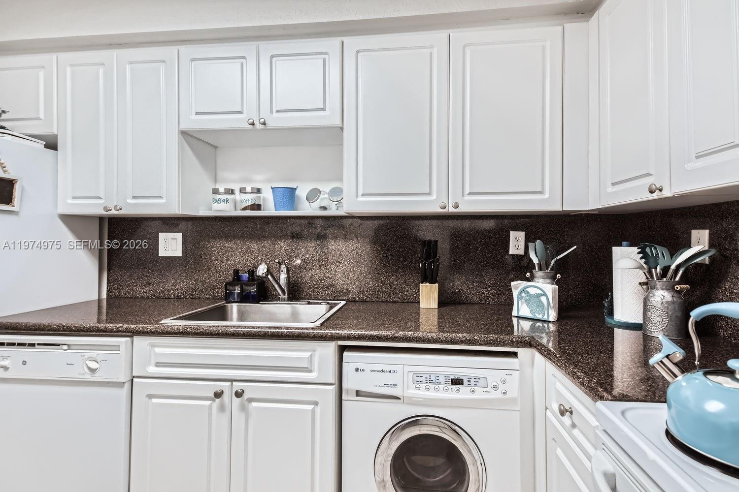 A kitchen features white cabinets, dark granite countertops, a stainless steel sink, and an integrated washer — 2501 S Ocean Dr, Hollywood FL 33019, HOLLYWOOD, FL