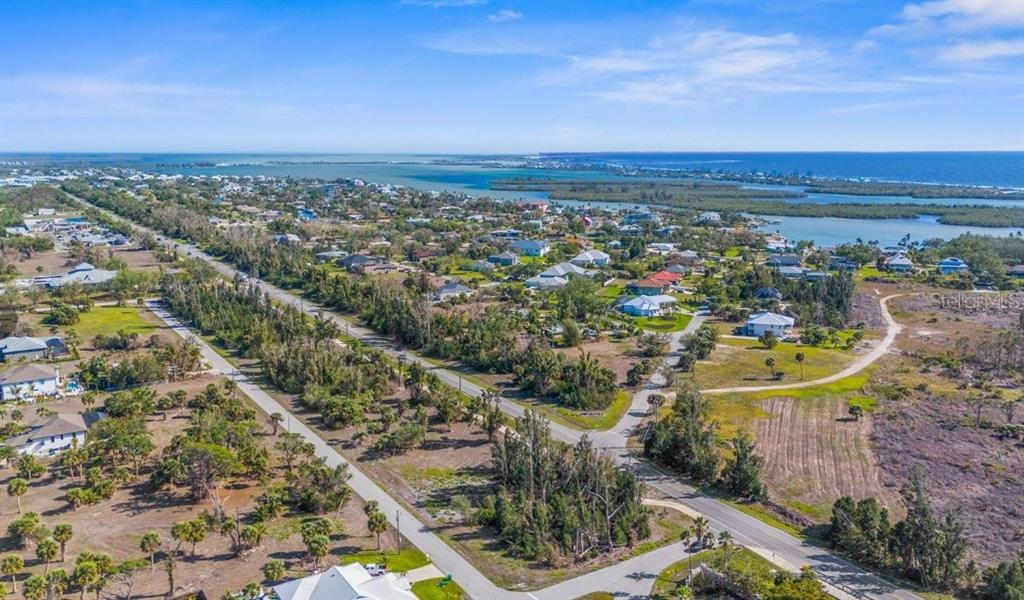 An aerial view shows a coastal neighborhood with houses, trees, and a nearby body of water — 50 BONITA STREET, PLACIDA, FL