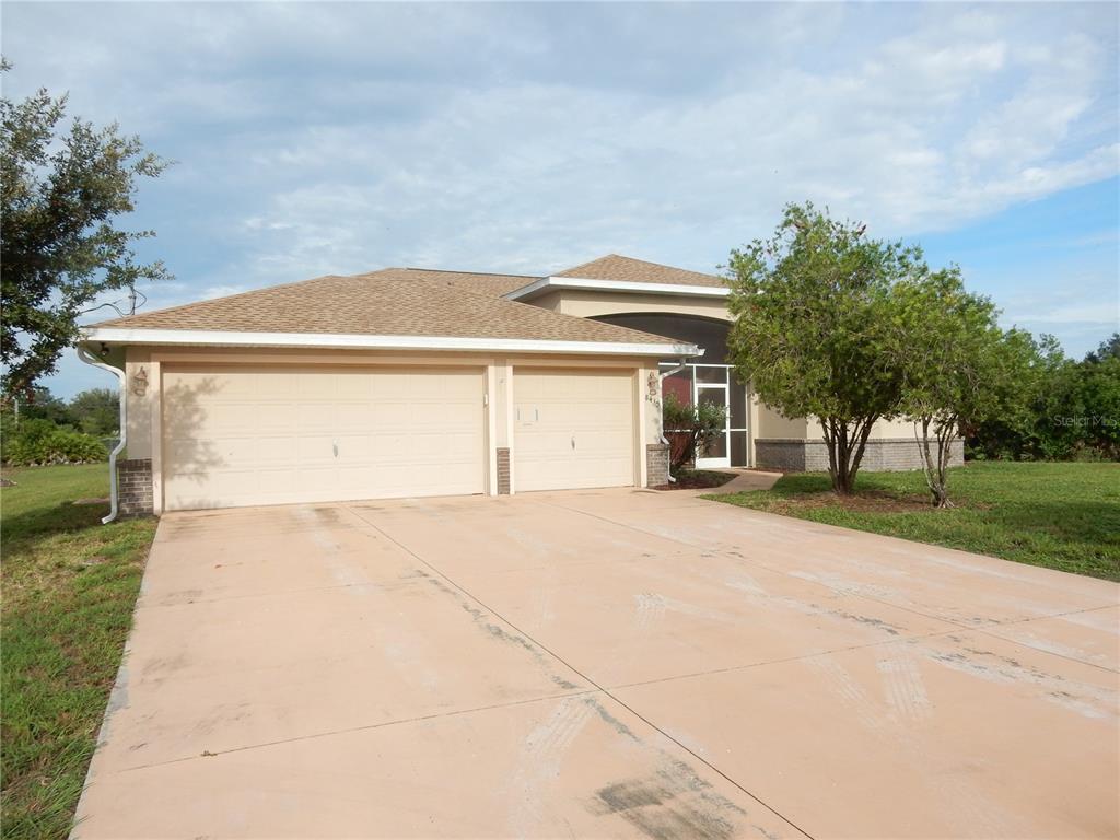 A single-story house with a two-car garage and a concrete driveway under a cloudy sky — 8430 ACORN BOULEVARD, PUNTA GORDA, FL