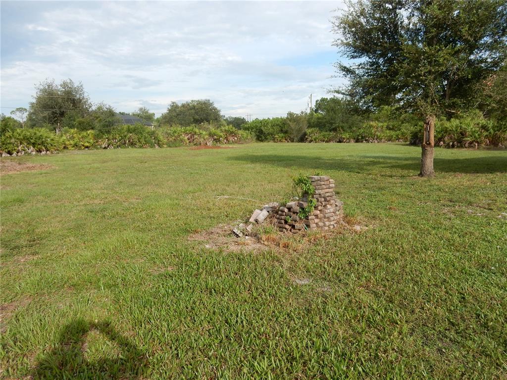 A grassy, open lot features a small pile of stacked bricks in the center — 8430 ACORN BOULEVARD, PUNTA GORDA, FL