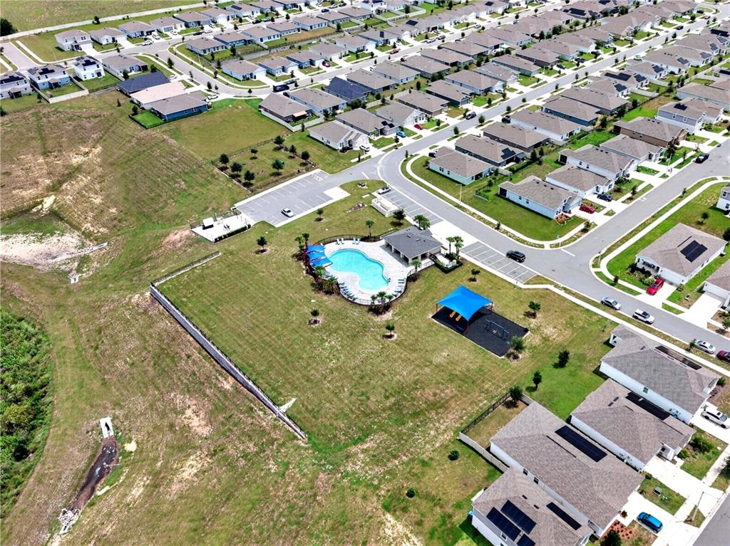 An aerial view shows a residential neighborhood with a community swimming pool and playground — 598 TANARO LANE, HAINES CITY, FL