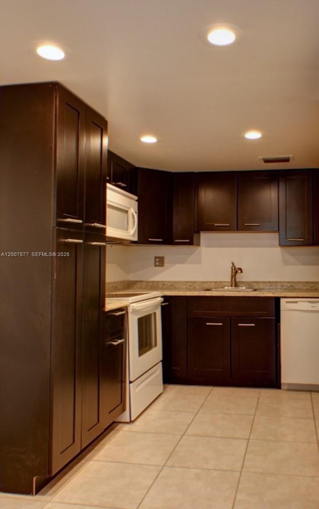 A kitchen features dark wood cabinets, white appliances, and light-colored tile flooring — 8020 SW 17th Pl # 5, Davie FL 33324, DAVIE, FL