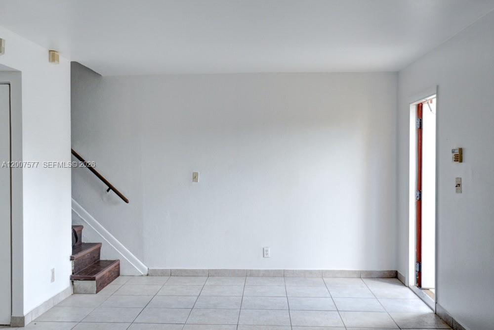 An entryway features white walls, light-colored floor tiles, a wooden staircase, and a glass door — 8020 SW 17th Pl # 5, Davie FL 33324, DAVIE, FL
