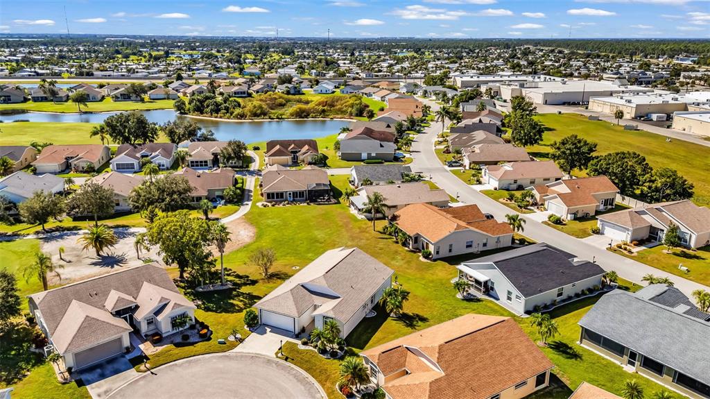 An aerial view shows a suburban neighborhood with houses, a pond, and paved streets — 1713 PALACE COURT, PUNTA GORDA, FL