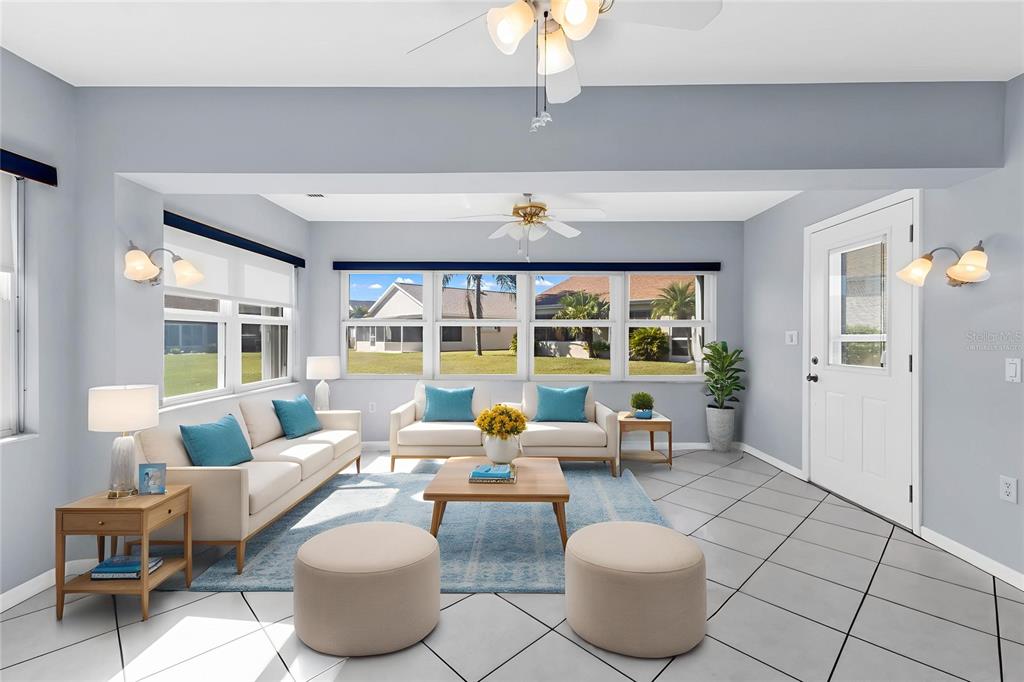 A bright living room features light-colored sofas, a coffee table, and tile flooring — 1713 PALACE COURT, PUNTA GORDA, FL