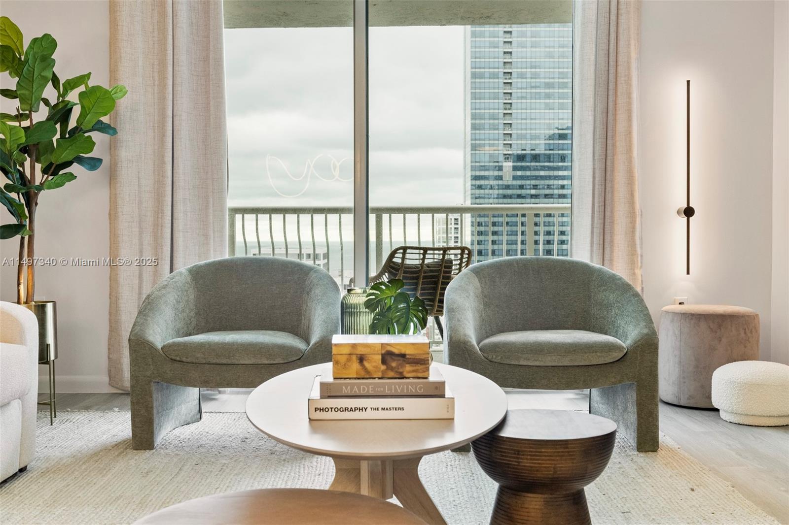A living room features two sage green armchairs, a round coffee table, and balcony views — 1200 Brickell Bay Dr # 3619, Miami FL 33131, MIAMI, FL