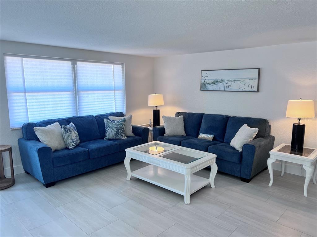 A living room features two blue sofas, a white coffee table, and two lamps — 6154 MIDNIGHT PASS ROAD UNIT B06, SARASOTA, FL