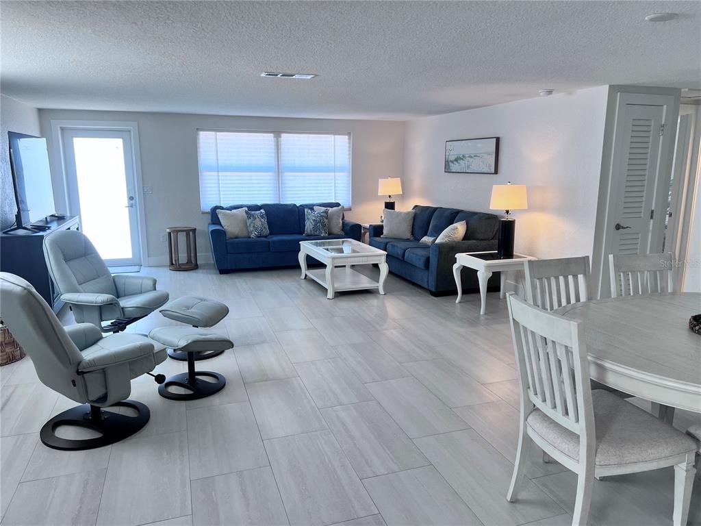 A living room features two blue sofas, two light-colored recliners, and light-toned tile flooring — 6154 MIDNIGHT PASS ROAD UNIT B06, SARASOTA, FL