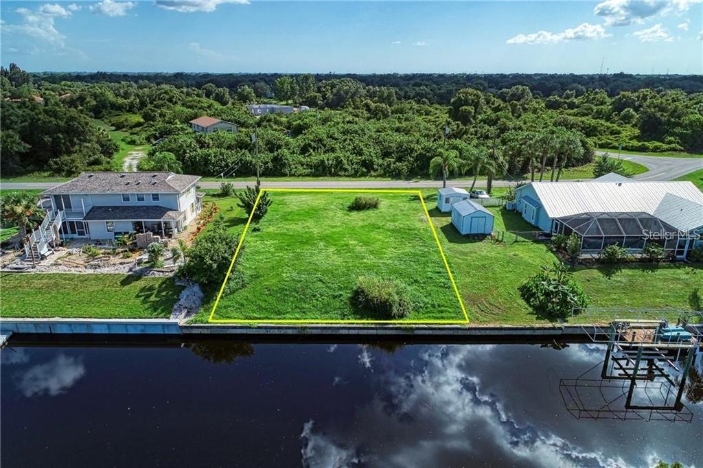 An aerial view shows a vacant, rectangular waterfront lot outlined in yellow between two houses — 27202 SAN MARCO DRIVE, PUNTA GORDA, FL