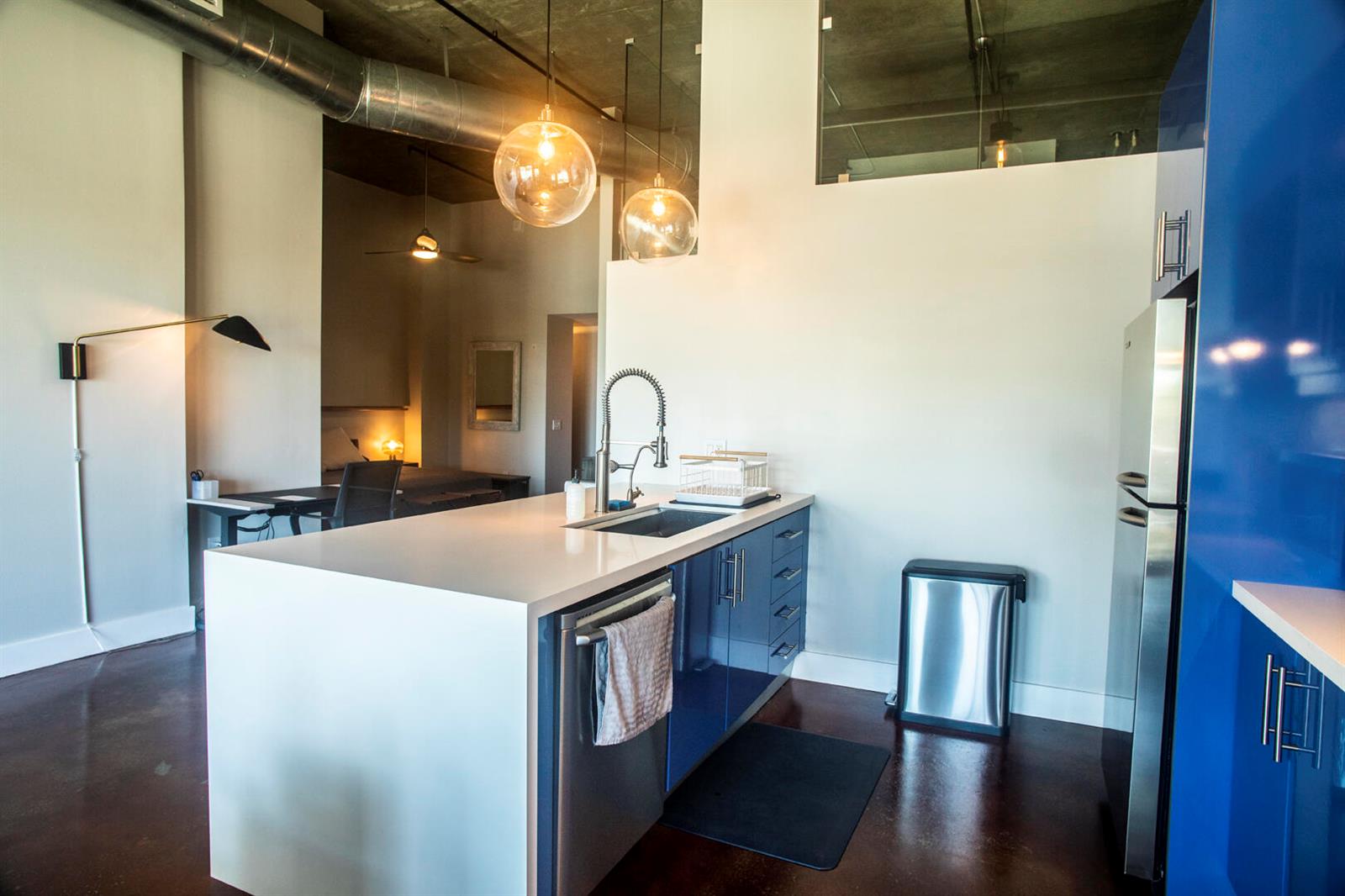 A modern kitchen island with blue cabinets and a white countertop sits in an apartment — 185 NE 4th Avenue # 204, Delray Beach FL 33483, DELRAY BEACH, FL