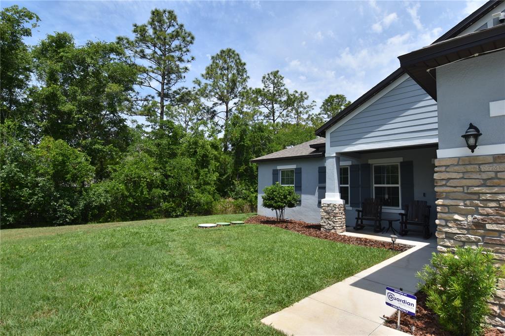 A single-story house with a gray exterior, stone accents, and a two-car garage — 14241 RAVINE AVENUE, WEEKI WACHEE, FL