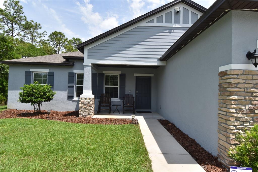 A single-story house with a gray stucco exterior, stone accents, and a two-car garage — 14241 RAVINE AVENUE, WEEKI WACHEE, FL