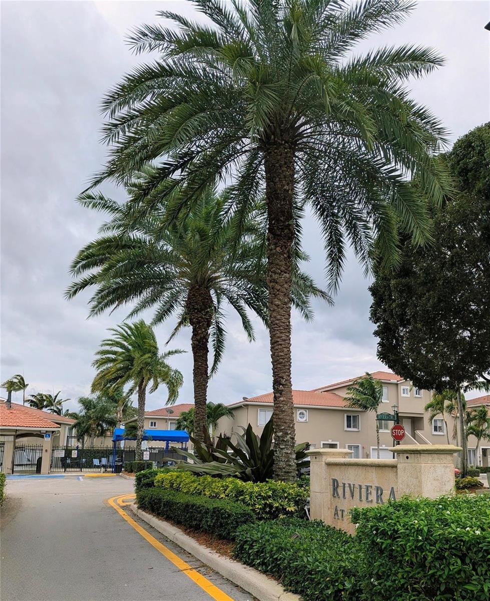 A paved entrance road leads to a community sign for Riviera at a residential complex — 158 Riviera Circle # 3, Weston FL 33326, WESTON, FL