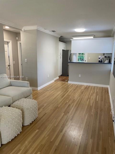 A living room with hardwood floors, a sofa, two ottomans, and an open kitchen counter — 5886 SW 42 St, Miami FL 33155, MIAMI, FL