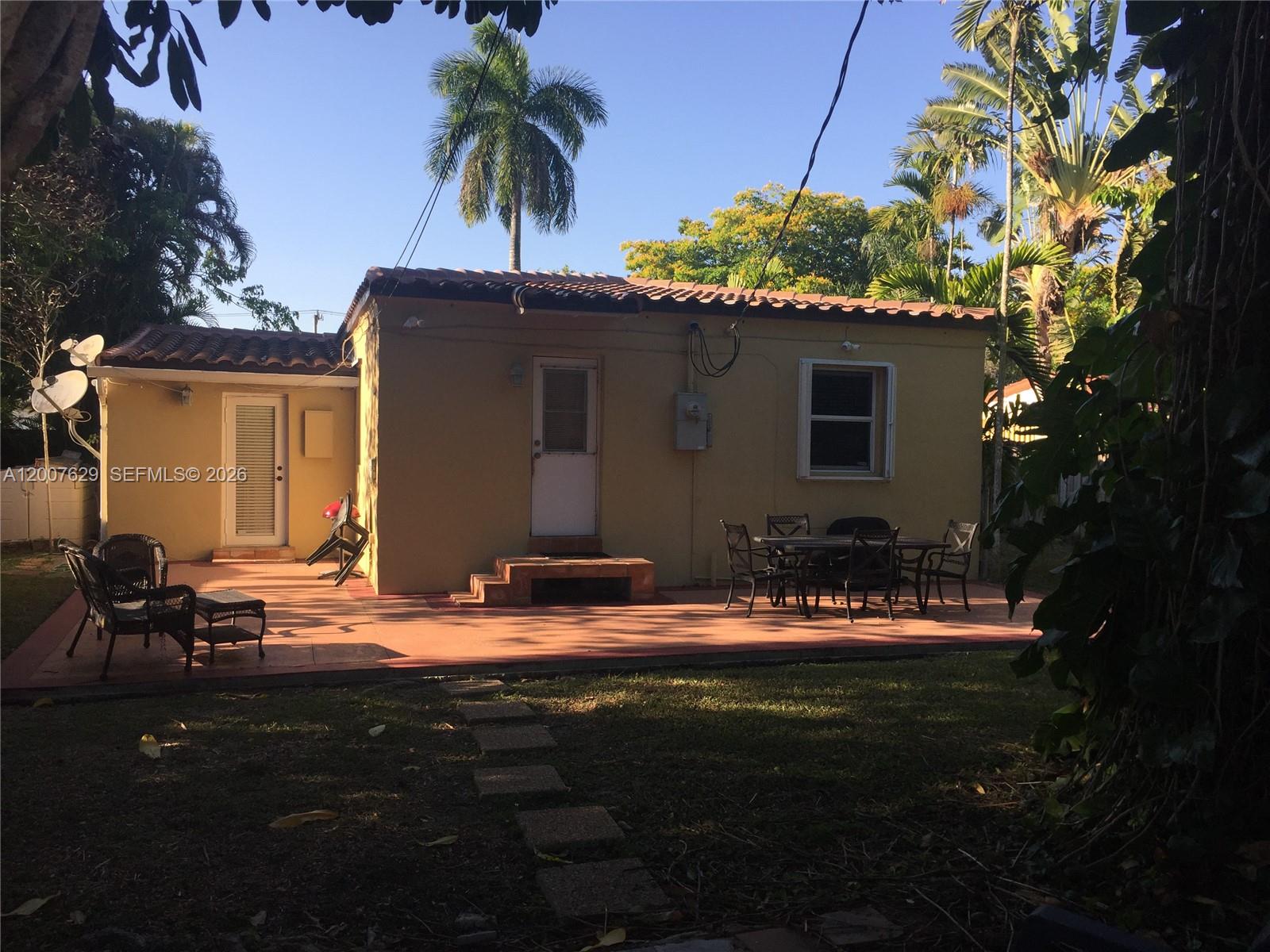 The exterior of a yellow house features a patio, outdoor furniture, and palm trees — 5886 SW 42 St, Miami FL 33155, MIAMI, FL