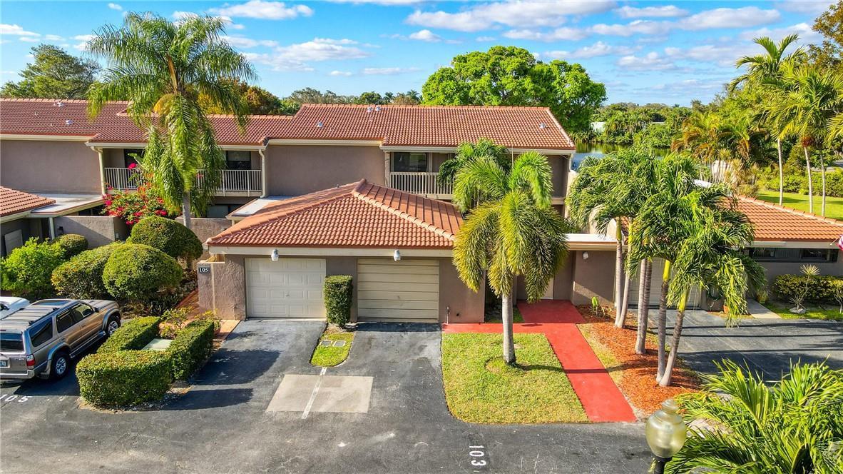 An exterior view of a two-story townhouse complex with tiled roofs, garages, and palm trees — 103 St Andrews Road, Hollywood FL 33021, HOLLYWOOD, FL