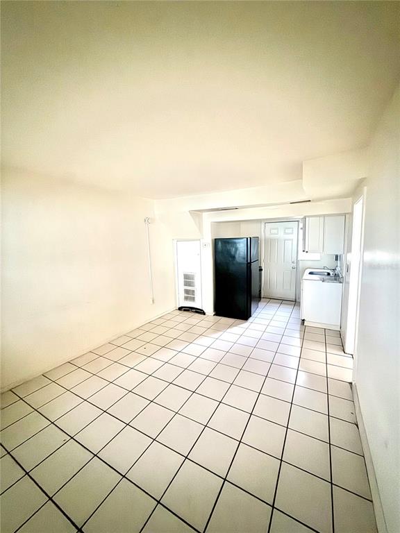 A small kitchen and dining area features white tiled floors and a black refrigerator — 1931 7TH STREET S, ST PETERSBURG, FL
