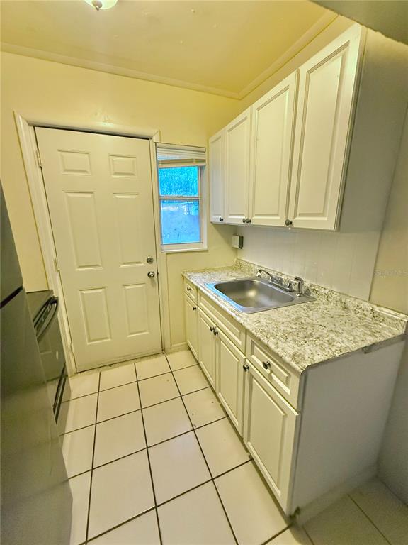 A kitchen features white cabinets, a stainless steel sink, granite-look countertops, and tiled flooring — 1931 7TH STREET S, ST PETERSBURG, FL