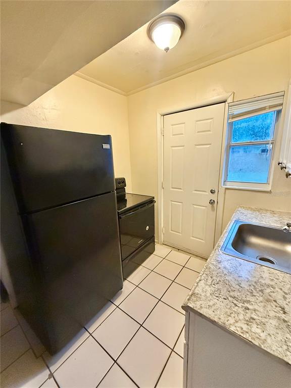A kitchen featuring a black refrigerator, a black stove, a sink, and tiled flooring — 1931 7TH STREET S, ST PETERSBURG, FL